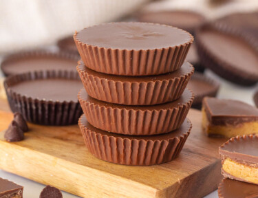 Stacked Homemade Reese's Peanut Butter Cups on a board.