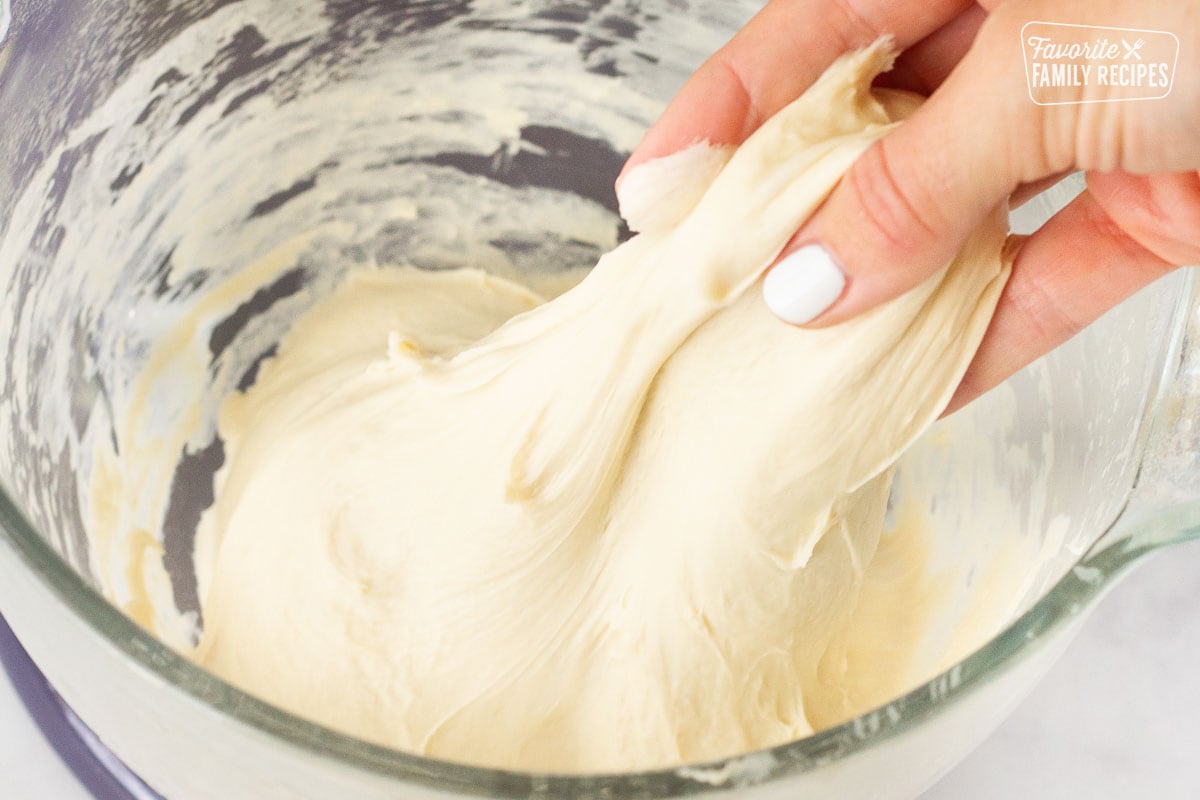 Hand stretching dough out of mixing bowl for Subway Bread.