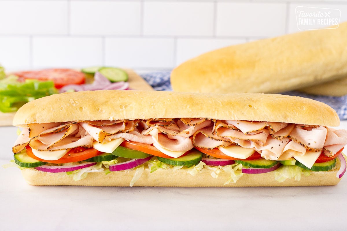 Full Subway Bread footlong sandwich with meat, cheese and cut up vegetables.