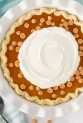 Top view of a full Butterscotch Pie with butterscotch syrup, butterscotch chips and whipped cream.