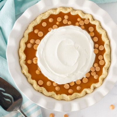Top view of a full Butterscotch Pie with butterscotch syrup, butterscotch chips and whipped cream.