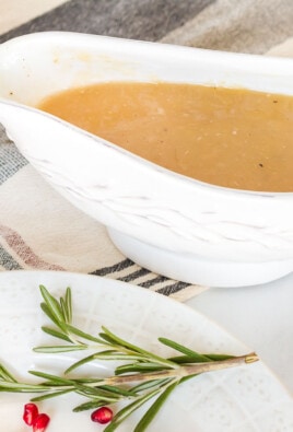 Turkey Gravy in a serving boat next to a dish of mashed potatoes.