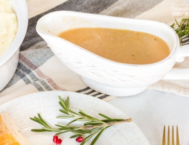 Turkey Gravy in a serving boat next to a dish of mashed potatoes.