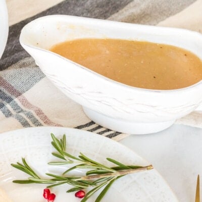 Turkey Gravy in a serving boat next to a dish of mashed potatoes.