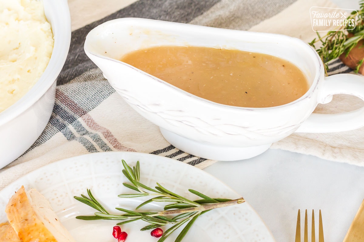 Turkey Gravy in a serving boat next to a dish of mashed potatoes.