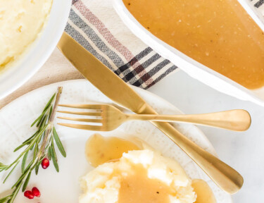 Top view of a Turkey Gravy boat next to a plate of mashed potatoes and gravy.