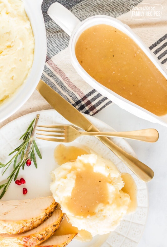 Top view of a Turkey Gravy boat next to a plate of mashed potatoes and gravy.