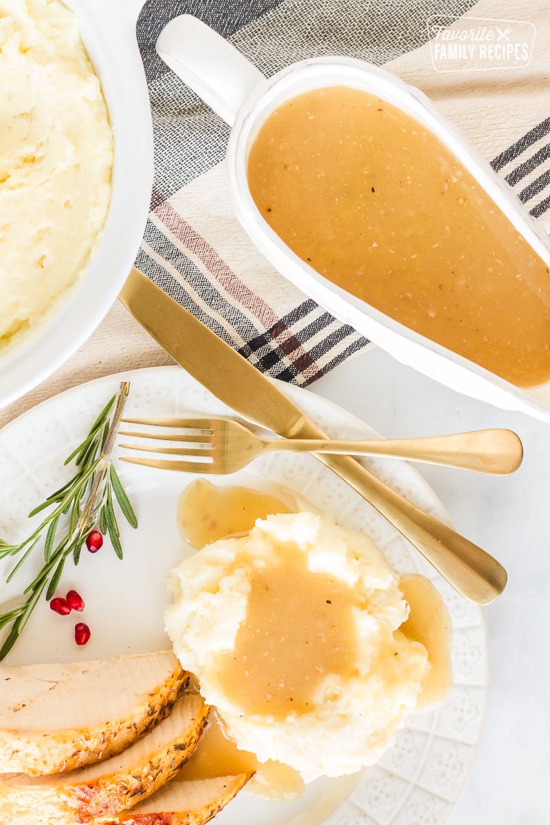 Top view of a Turkey Gravy boat next to a plate of mashed potatoes and gravy.