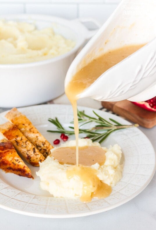 Turkey Gravy pouring on a plate of mashed potatoes and turkey.