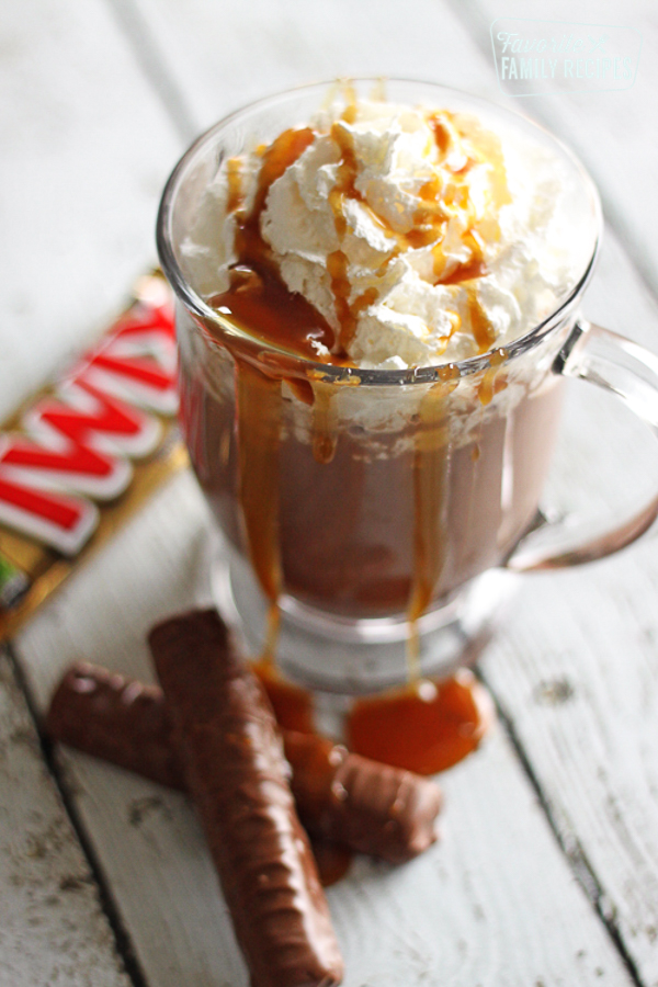 Twix candy bar hot chocolate in a glass cup.