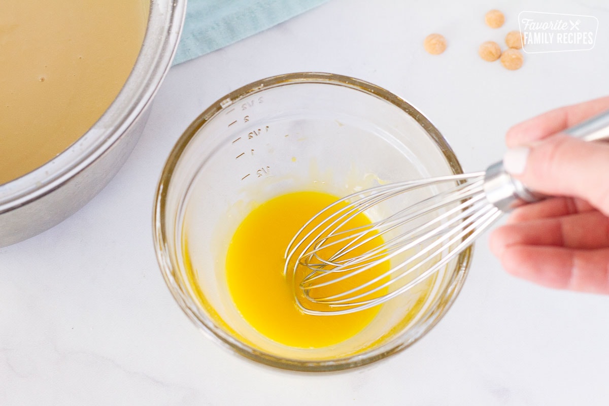 Hand whisking a bowl of egg yolks together for Butterscotch Pie filling.