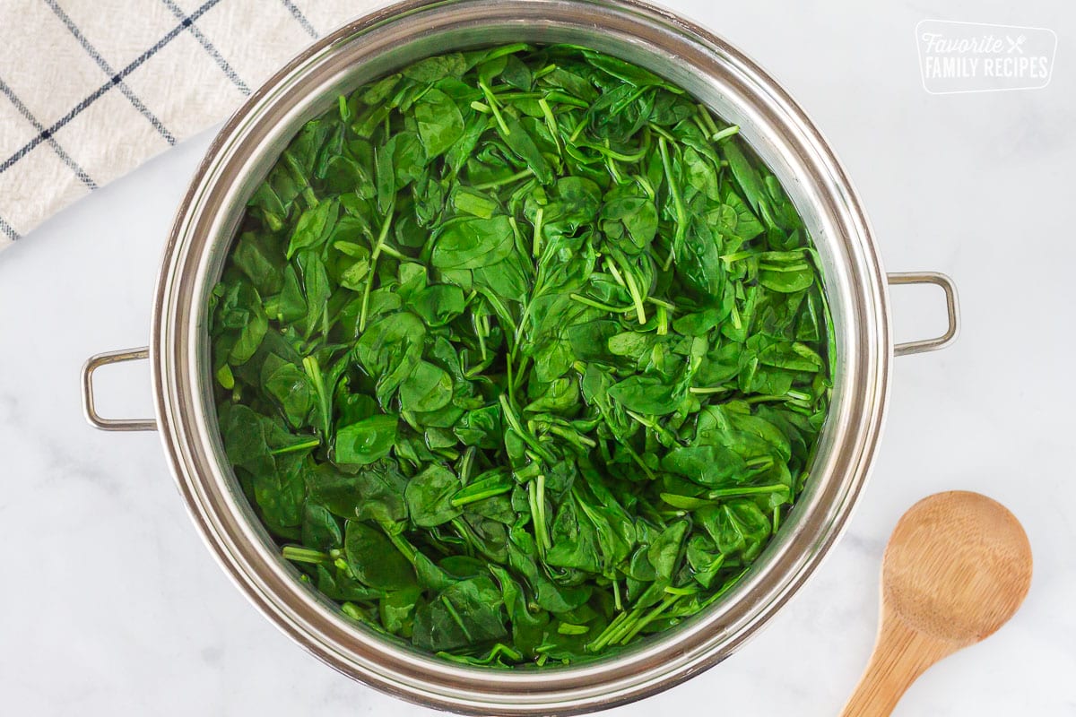 Large pot of wilted baby spinach in hot water to make Creamed Spinach.