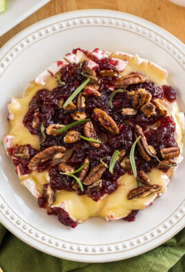 Baked Brie topped with honey, cranberry sauce, pecans, and rosemary