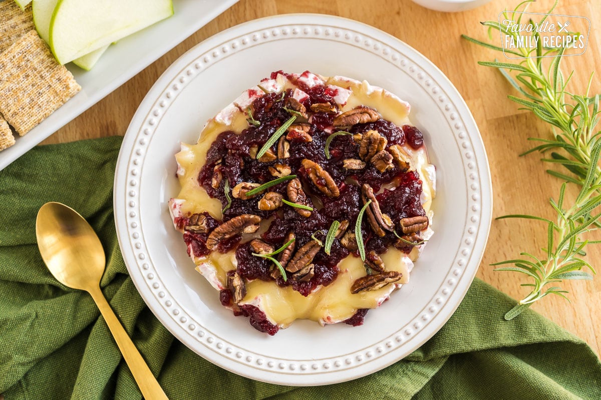 Baked Brie topped with honey, cranberry sauce, pecans, and rosemary