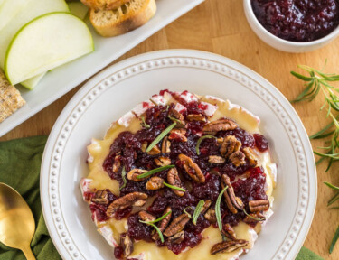 Baked Brie topped with honey, cranberry sauce, pecans, and rosemary