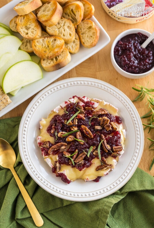 Baked Brie topped with honey, cranberry sauce, pecans, and rosemary