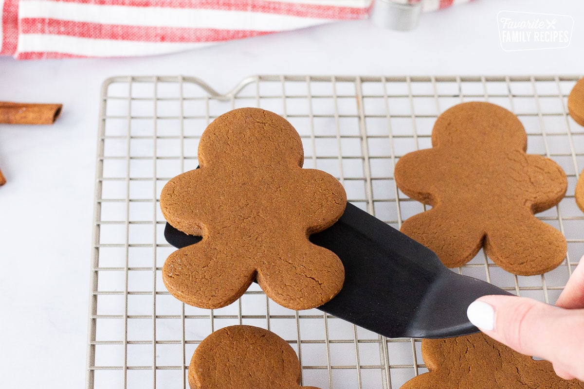 Spatula holding a Baked Gingerbread man cookie over a cooling rack.