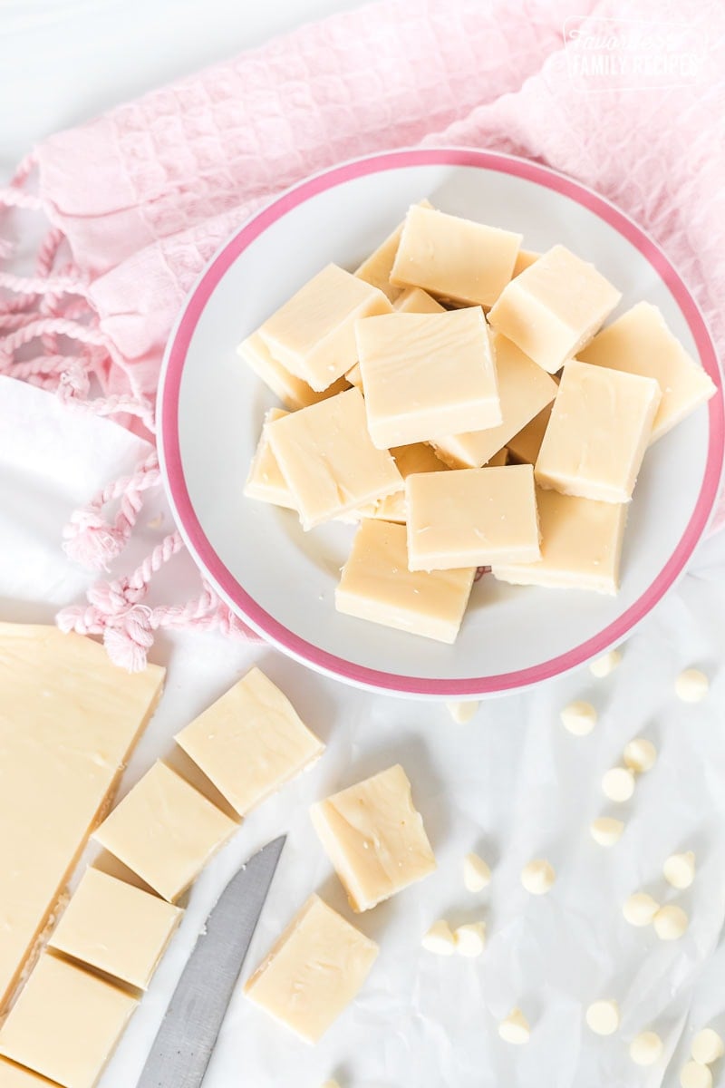 White vanilla fudge on a plate next to a block of fudge.