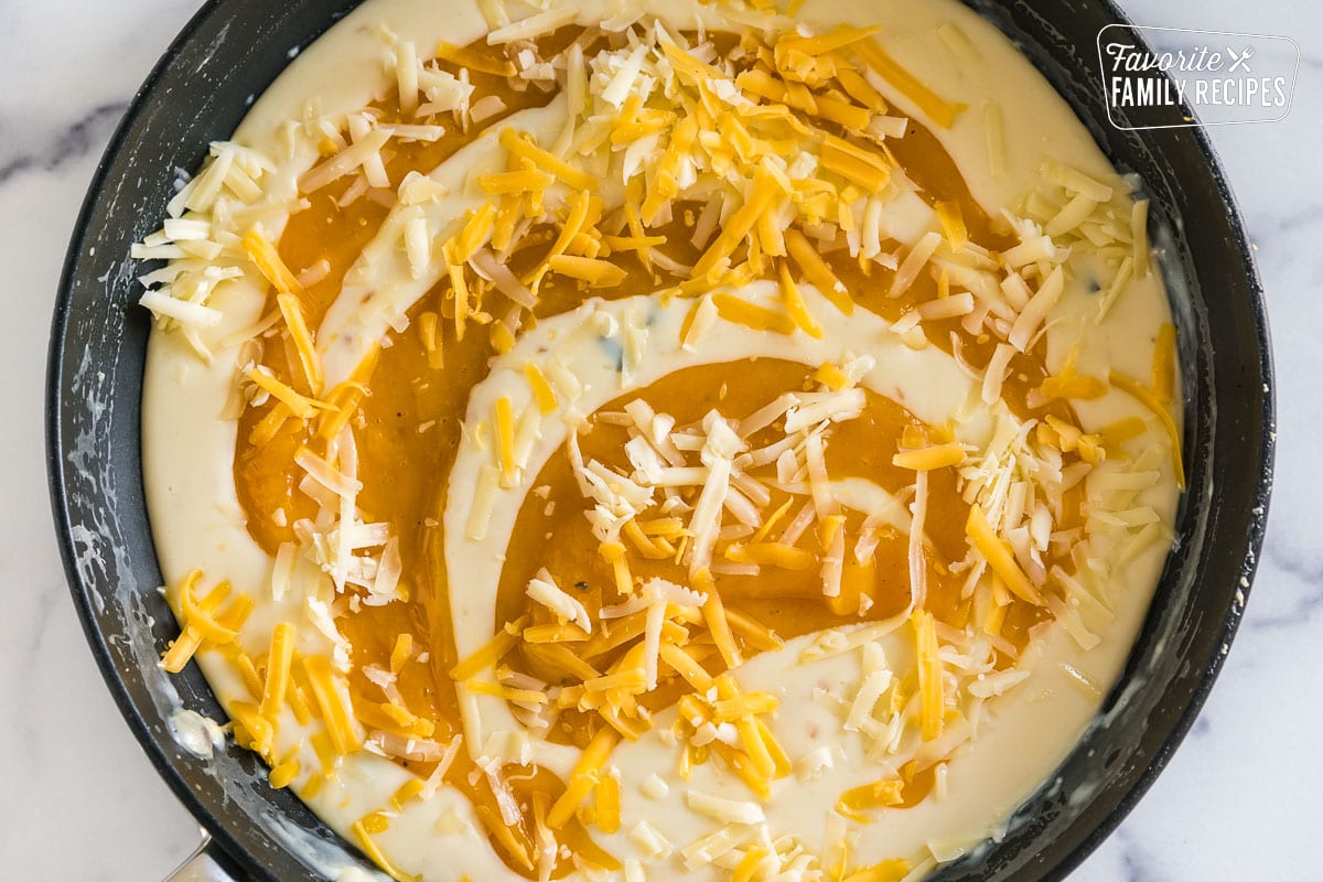 Cream sauce in a large skillet with pureed butternut squash and shredded cheese on top