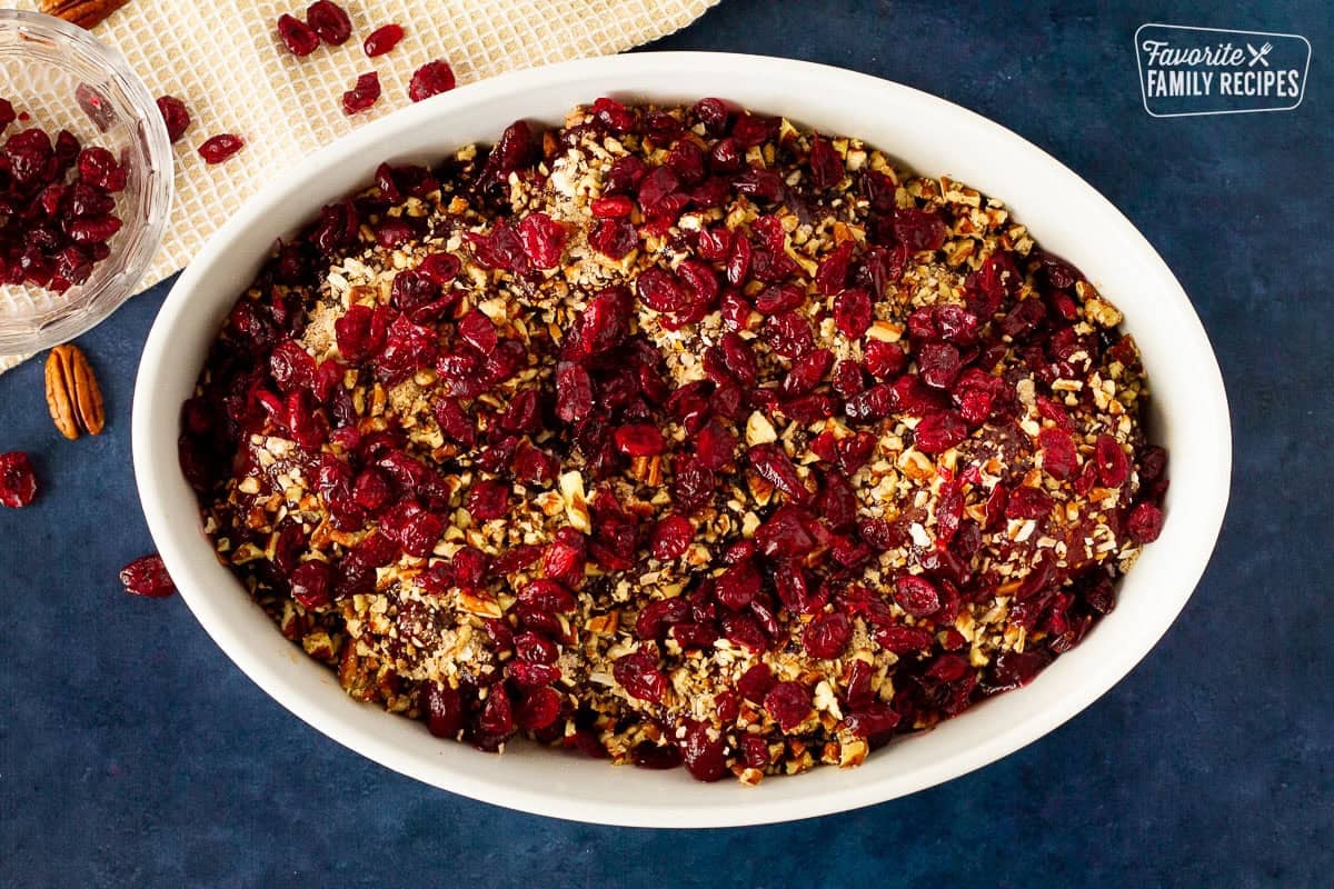 Glass dish with craisins, pecans and soup mix on top of chicken.