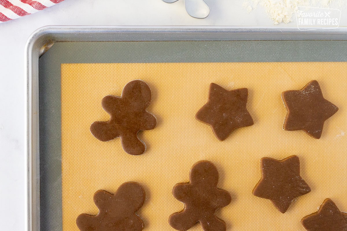 Cookie sheet with a silicone mat of unbaked Gingerbread cut out Cookies.
