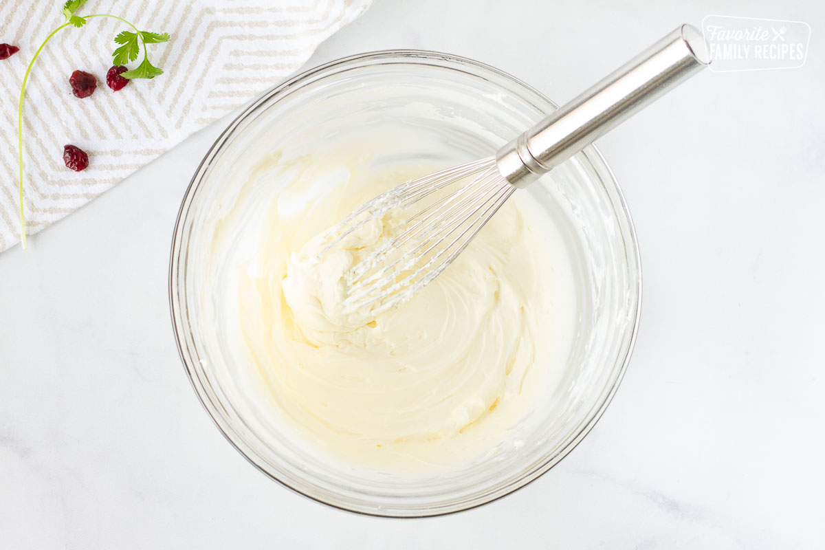 Bowl of whipped cream cheese with a whisk.