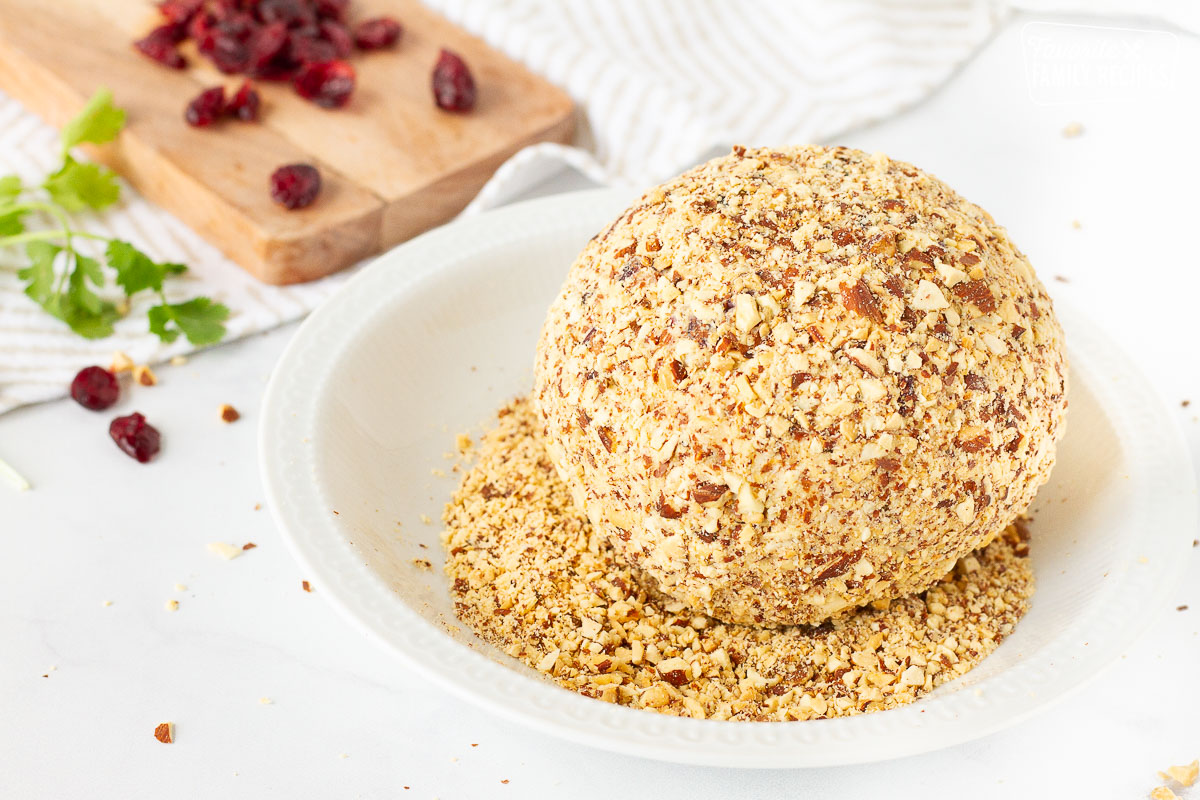Cranberry Almond Bacon Cheese Ball in a bowl of chopped almonds.