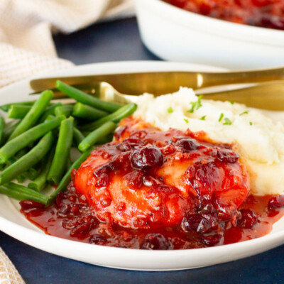 Cranberry Chicken on a dinner plate with mashed potatoes and green beans.
