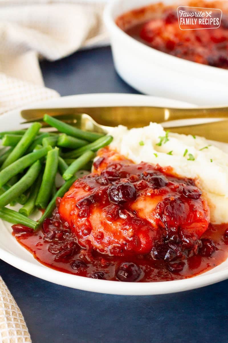 Cranberry Chicken on a plate of mashed potatoes and green beans.