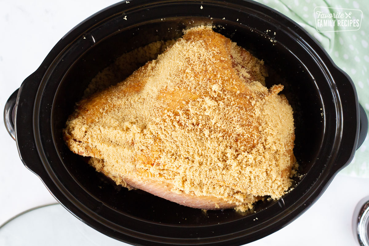 Slow Cooker with brown sugar on top of a Spiral Ham.