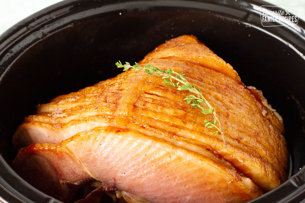 Spiral ham in slow cooker garnished with thyme.