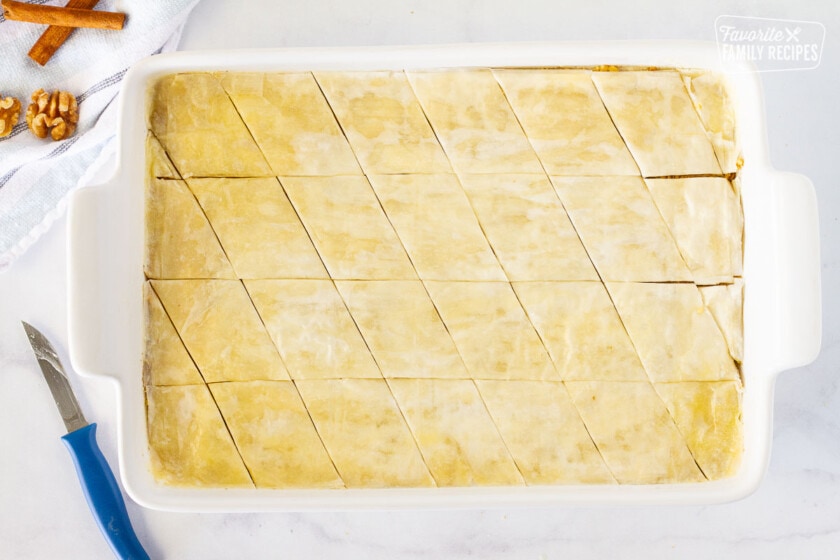 Diamond slice design on top of unbaked Baklava in a glass baking dish.
