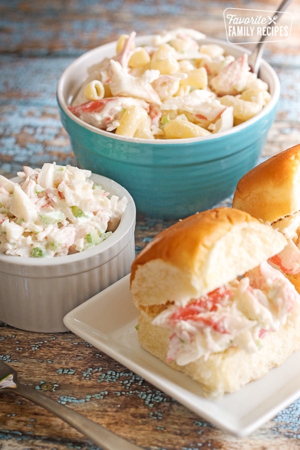 Crab salad sandwiches, crab salad in a bowl, and crab salad with pasta in a bowl on a table.