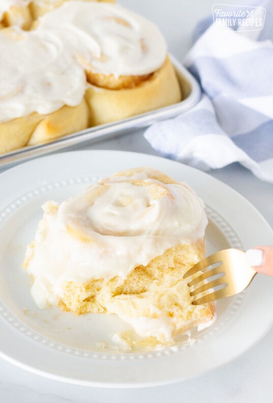 Fork cutting into a Homemade Cinnamon Roll.