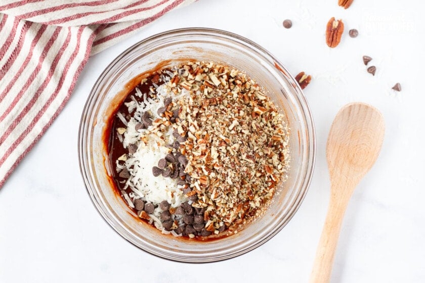 Bowl of pecans, coconut and chocolate chips on German Chocolate Pie filling mixture.