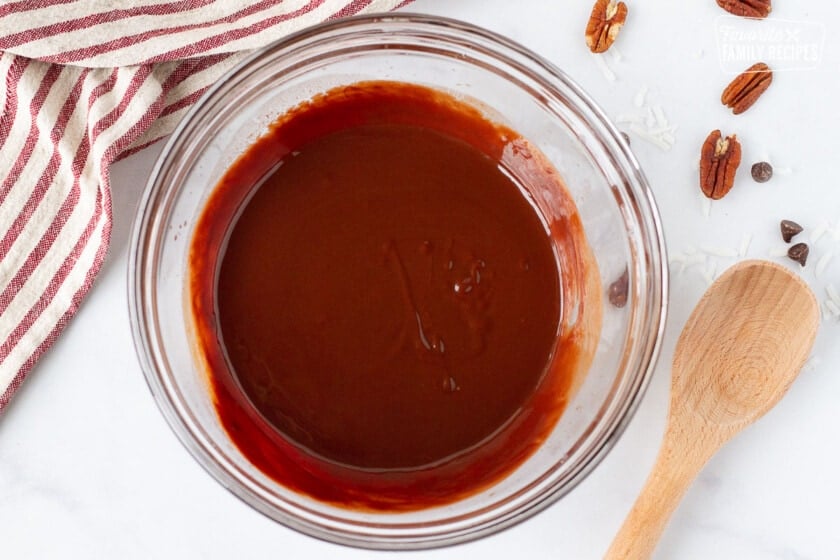 Bowl of melted butter and chocolate for German Chocolate Pie filling. Wooden spoon on the side.