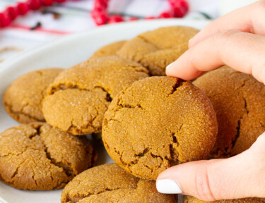 Hand grabbing a Molasses Cookie from a plate.