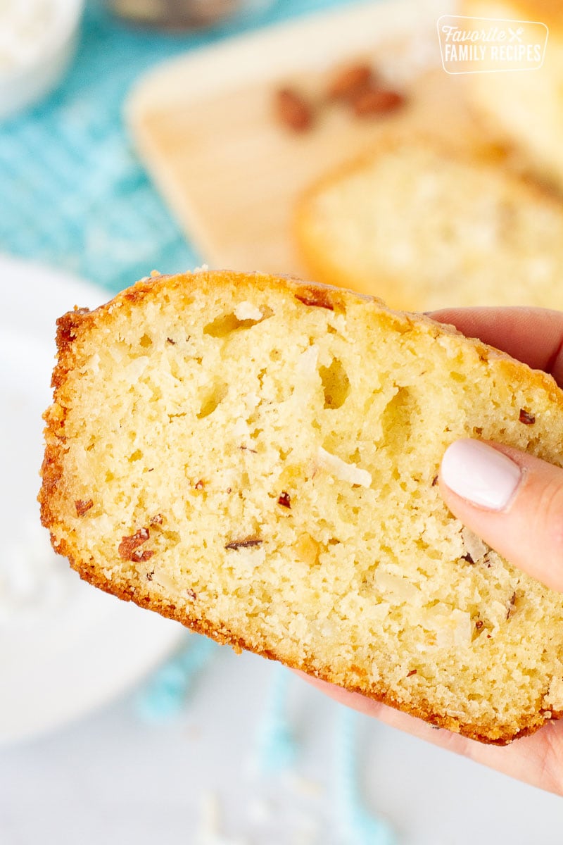 Hand holding a slice of Sweet Coconut Bread.