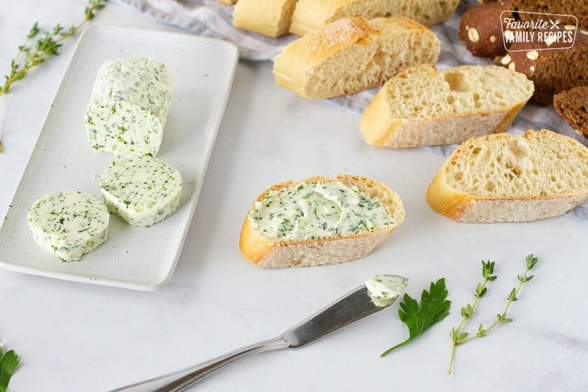 Herbed Butter spread on sliced bread next to a butter dish with sliced Herbed Butter.