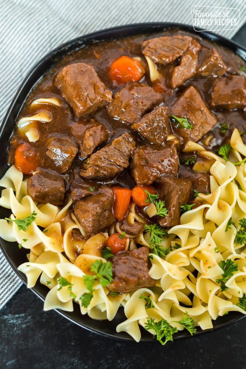 Hungarian Instant Pot goulash on a black plate with noodles.