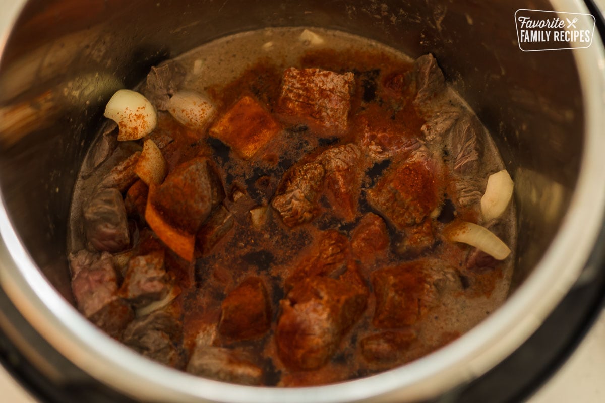Beef, onions, and seasoning in an Instant Pot to make goulash