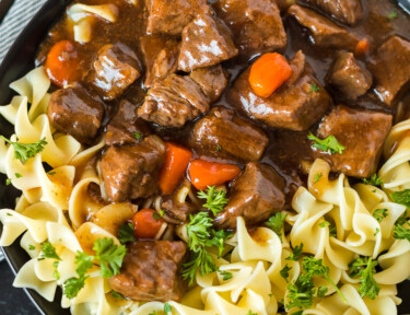 A plate of Instant Pot Goulash with egg noodles, tender stew meat, carrots, and onion