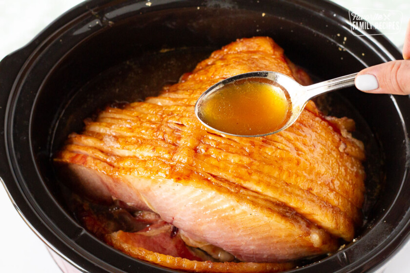 Spoon with juices of Spiral Ham in the Crockpot.