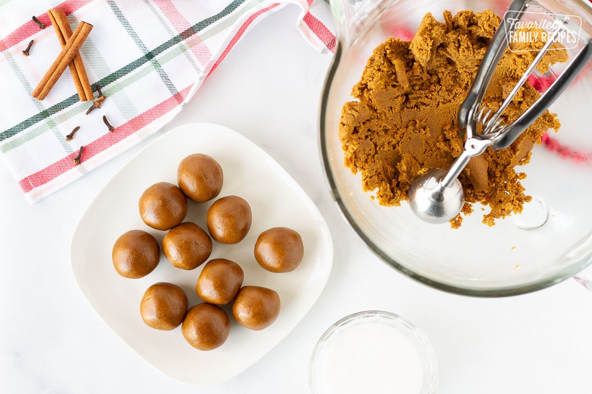 Molasses Cookie dough balls on a plate next to a bowl of dough.