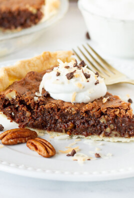 German Chocolate Pie slice on a plate topped with whipped cream, toasted coconut and chocolate.