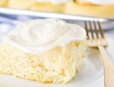 Homemade Cinnamon Roll on a plate with cream cheese frosting.