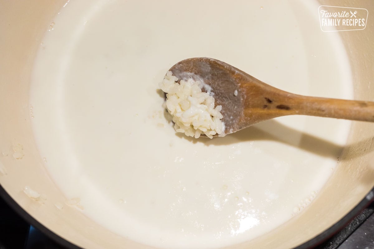 Softened rice on a spoon to make rice pudding