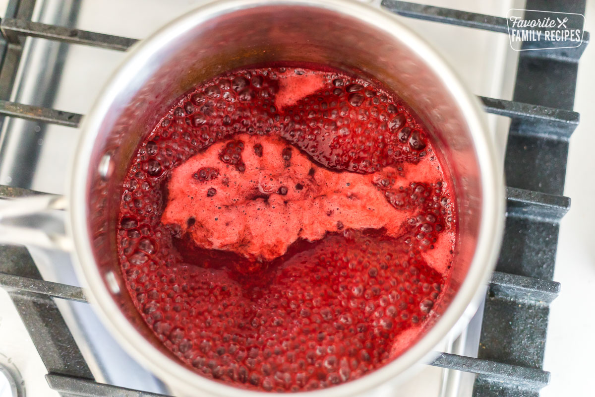 Raspberries being simmered into a sauce on a stovetop