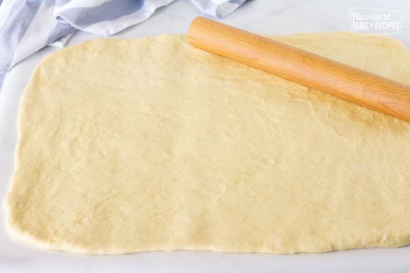 Rolling pin rolling out Cinnamon Roll dough into a rectangle.