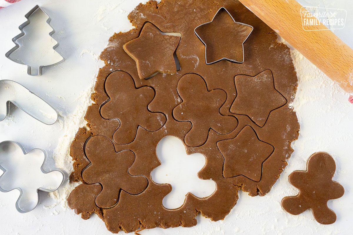 Rolled out Gingerbread cookie dough with cut out shapes. Cookie cutters and rolling pin on the side.
